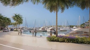 Een jachthaven met aangemeerde boten, palmbomen en een modern gebouw met een gebogen dak.
