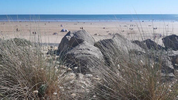Una platja amb roques i vegetació escassa.