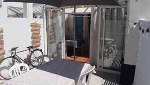 Un balcó amb taula i cadires, una bicicleta i una pila de maons.