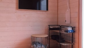 Una habitació petita amb una taula rodona, un moble prestatges negre i un televisor fixat a la paret.