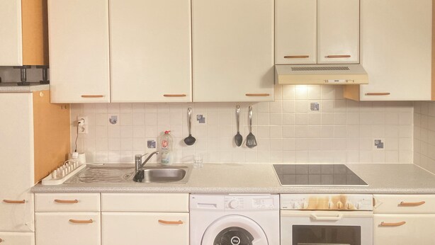 A kitchen with white cabinets, a built-in oven, a dishwasher, and a stainless steel sink. - Cosy, well-connected Flat near Vienna city center and the central train station (Vienna)