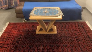 A room with a brown sofa, a blue bedspread, a small wooden table with a patterned cloth, and a red patterned rug. - Cosy, well-connected Flat near Vienna city center and the central train station (Vienna)