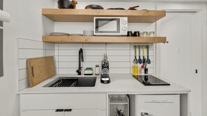 Eine moderne Küche mit weißen Schränken, einer Mikrowelle und Holzregalen über der Arbeitsplatte.