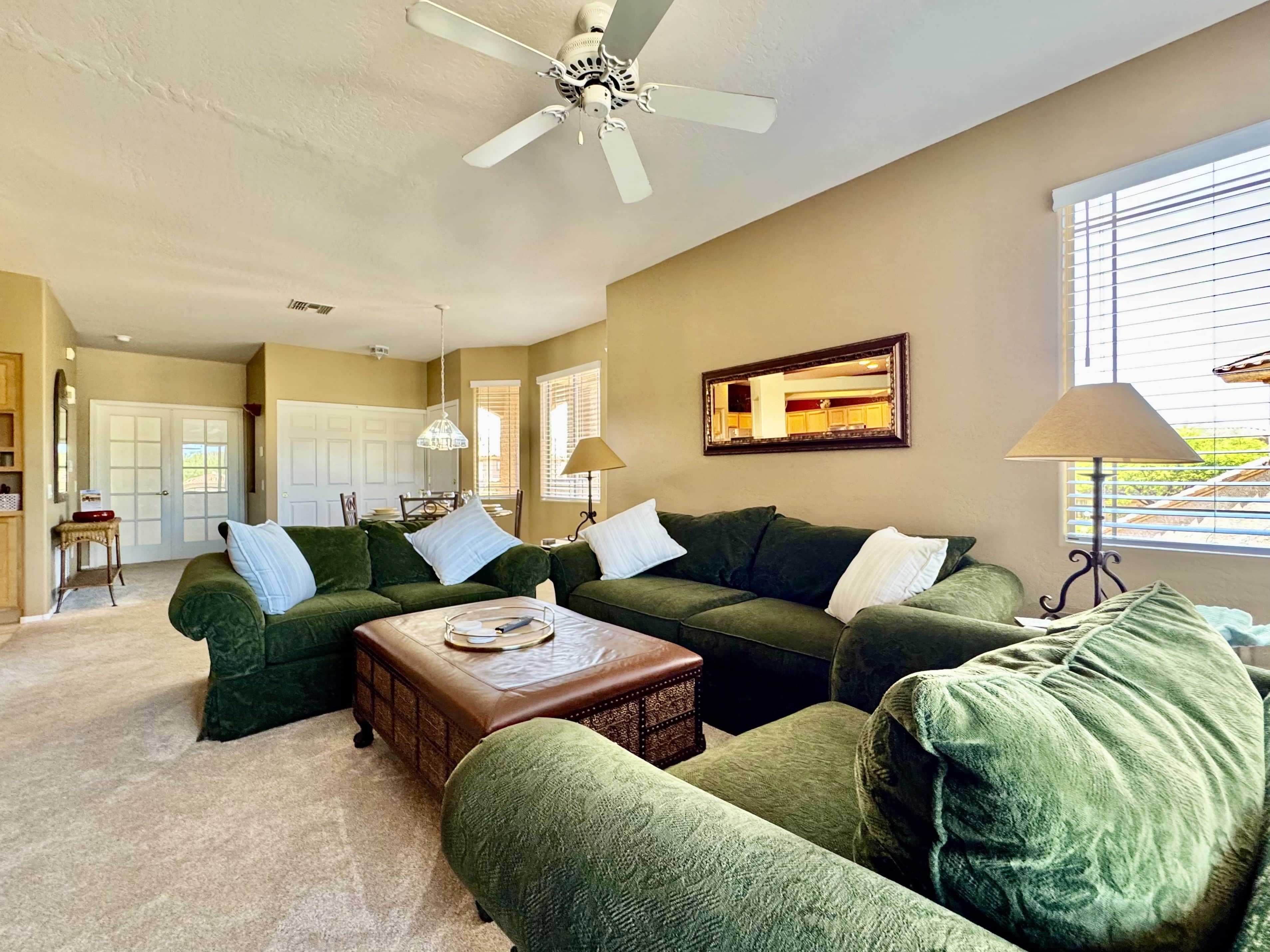A living room with green sofas, a coffee table, and a ceiling fan.