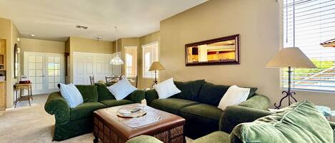 A living room with green sofas, a coffee table, and a ceiling fan.