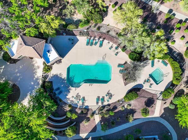 Vue aérienne d’un complexe hôtelier doté d’une piscine centrale, de plusieurs espaces de détente et de jardins aménagés.