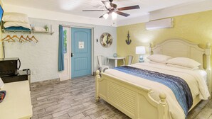 A bedroom with a bed, a ceiling fan, a small table with chairs, a microwave, and a blue door. - Siesta Key Palms Hotel - Gran Studio (Sarasota)