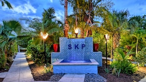 Un espace aménagé avec un élément aquatique, un sentier et un panneau portant les lettres « SKP ».