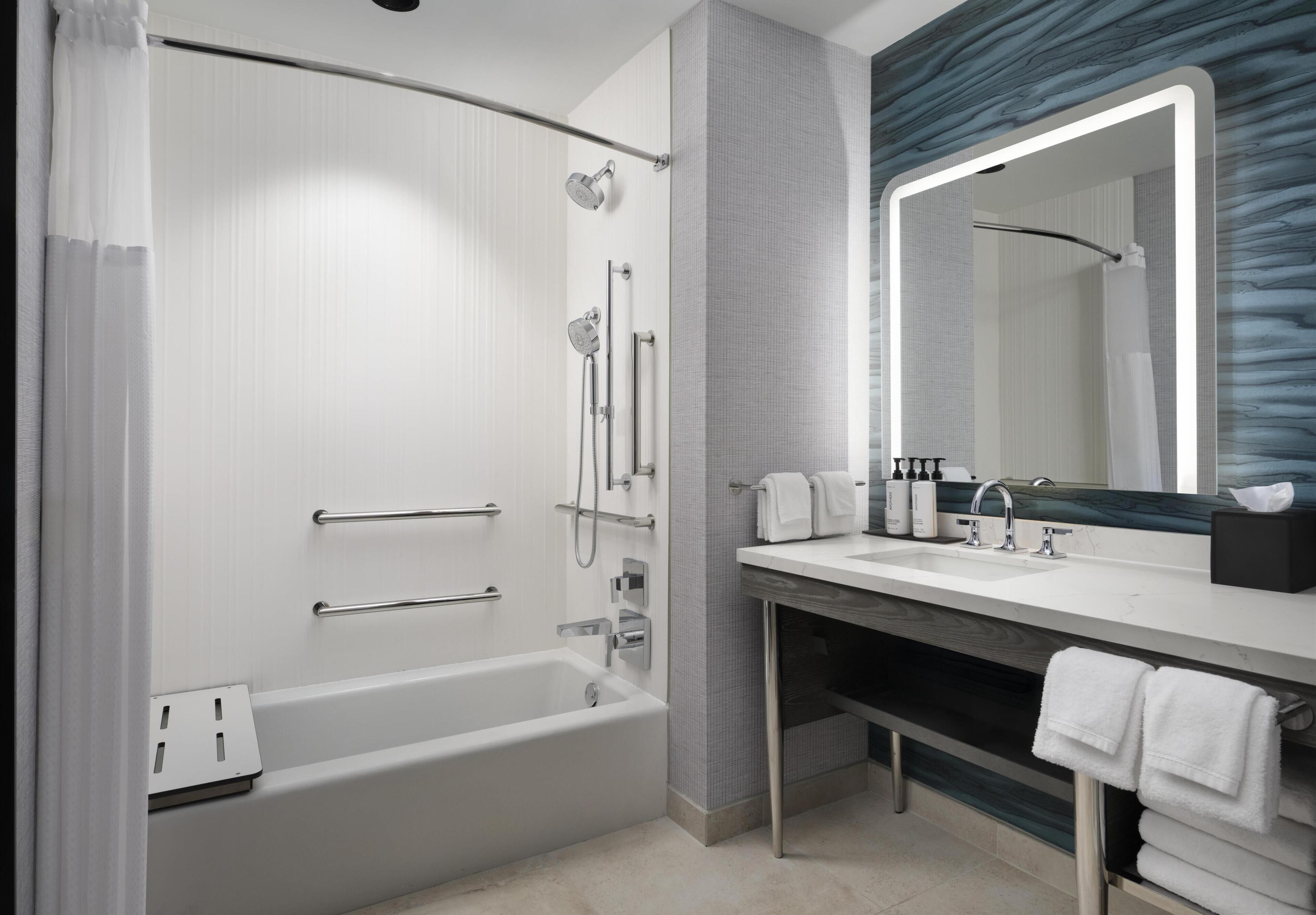 Un bagno moderno con vasca, doccia, lavabo e un grande specchio.