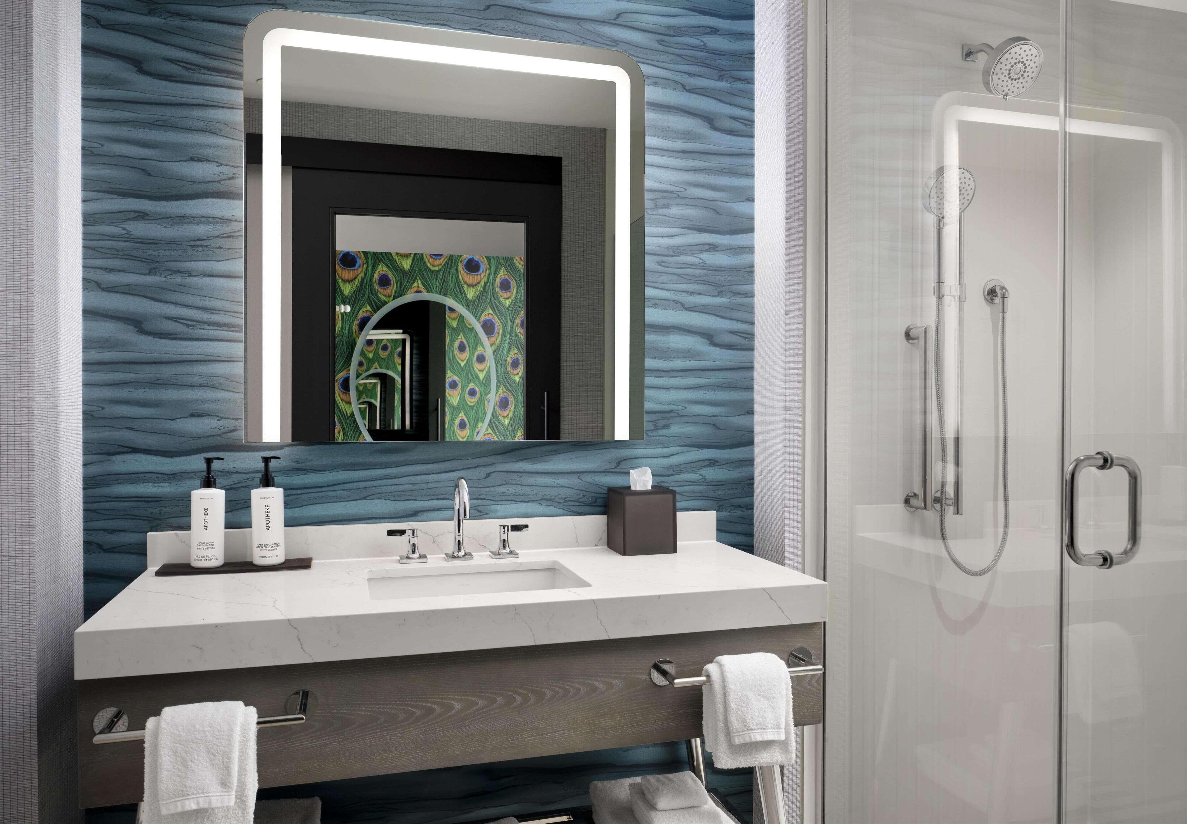 Une salle de bain moderne avec un meuble-lavabo, un évier, un miroir et une douche.