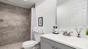 Une salle de bain moderne équipée d’une douche, de toilettes et d’un meuble-lavabo.
