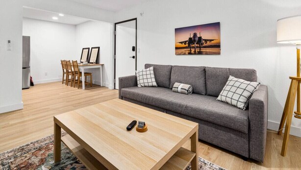 En moderne stue med en grå sofa, et træbord og et billede på væggen.