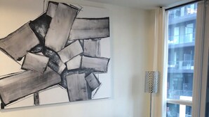 Ein modernes Wohnzimmer mit einem grauen Ecksofa, einem weißen Couchtisch und einem großen abstrakten Gemälde an der Wand.