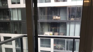 Blick vom Balkon mit Terrakottafliesen auf ein modernes Gebäude mit mehreren Fenstern und Balkonen.