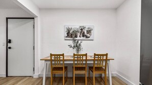 A dining area with a wooden table and chairs, a white wall, and a door. - Designer Loft in Pueblo – Central Modern Comfort (Pueblo)