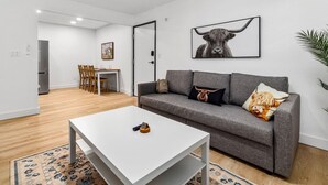 Una sala de estar moderna con un sofá gris, una mesa de centro blanca y una obra de arte enmarcada de un toro en la pared.