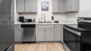 A modern kitchen with grey cabinets, a stainless steel dishwasher, a black oven, and a microwave. - NEW ! Stylish Loft in DT Pueblo – Sleeps up to 6 (Pueblo)