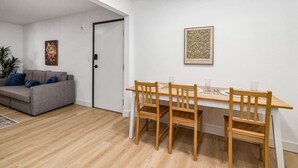 A modern living room with a grey sofa, wooden dining table, and chairs. - NEW ! Stylish Loft in DT Pueblo – Sleeps up to 6 (Pueblo)