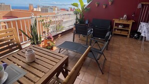 A terrace with a wooden table and chairs, a small table with a lantern, and potted plants. - Modern Apartment with Large Flower Terrace & Pool – Chayofa, Tenerife (Chayofa)
