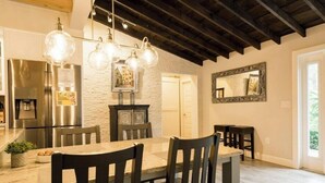 Zona pranzo con tavolo e sedie in legno, parete in pietra e cucina moderna con elettrodomestici in acciaio inossidabile.