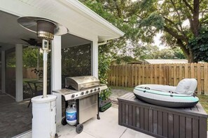 A covered outdoor patio with a grill, a propane tank, and an inflatable raft.