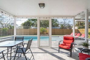 A covered patio with a pool, outdoor furniture, and a view of the backyard. - Private Heated Pool + Grill | Cozy Coastal (Sarasota)