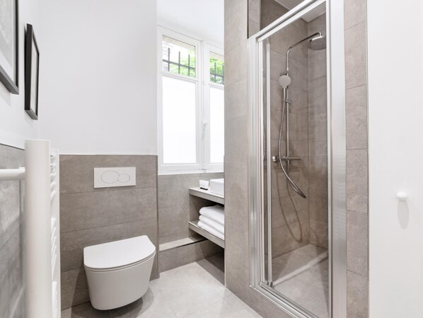 Une salle de bain moderne équipée de toilettes, d’une douche et d’une fenêtre.