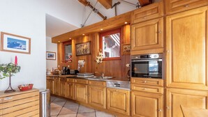 Eine Küche mit Holzausstattung, Edelstahlgeräten und Fliesenboden.