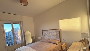 Une chambre à coucher avec un lit, un bureau, une chaise, un miroir et une fenêtre.