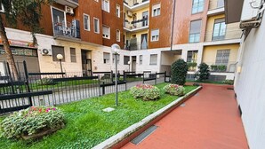 Une cour avec un chemin pavé, de l’herbe verte et des parterres de fleurs.