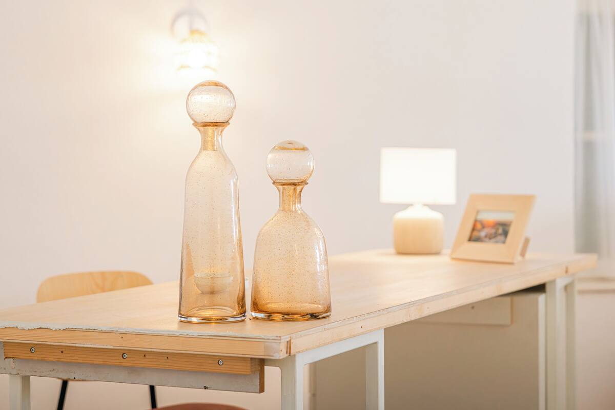 Een houten tafel met twee glazen flessen en een kaars.