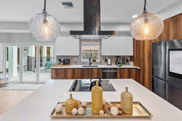 Una cocina moderna con una isla central, electrodomésticos de acero inoxidable y vistas al exterior.