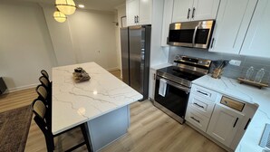 A modern kitchen with a marble countertop, stainless steel appliances, and white cabinetry. - Downtown Gem, Sunset & City Views, fully renovated (Atlanta)