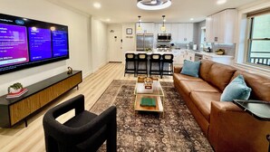 A modern living room with a flat-screen TV, a brown leather sofa, a coffee table, and a patterned rug. - Downtown Gem, Sunset & City Views, fully renovated (Atlanta)
