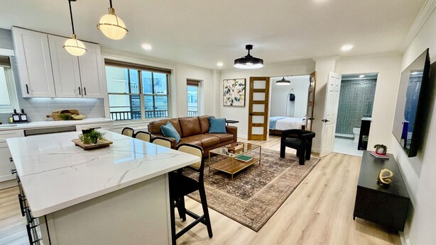 A modern kitchen with white cabinets, a marble island, and pendant lighting. - Downtown Gem, Sunset & City Views, fully renovated (Atlanta)