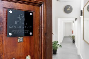 A wooden door with a plaque indicating 'Inns Relais San Giovanni' and a clock on the wall in the background. - RELAIS SAN GIOVANNI (Rome)