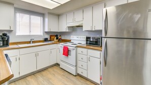 A modern kitchen with white cabinets, a stainless steel refrigerator, a microwave, and a stove. - Bullhead City Home - Near Colorado River! (Bullhead City)