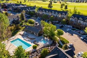 A residential area with a swimming pool, multiple houses, and a golf course in the background. - Modern Eden Condo Pool, Hot Tub, Gym & Game Room! (Eden)