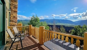 A wooden deck with chairs and a table, overlooking a mountainous landscape. - Modern Eden Condo Pool, Hot Tub, Gym & Game Room! (Eden)