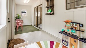 Un couloir avec un petit coin cuisine, une chaise, une plante en pot et une vue sur l’extérieur.