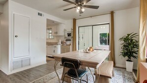 Un coin repas avec une table en bois, des chaises, un ventilateur de plafond et une plante en pot.