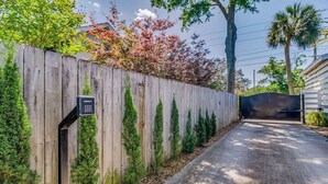 A wooden fence with a security keypad, a paved driveway, and a gate leading to a house. - Pensacola 1 BR Sleeps 2 Suite in East Hill (Pensacola)