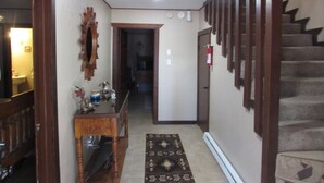 A hallway with a wooden staircase, a mirror, and a door leading to another room. - 2 Master Bedrooms-Full Bathrooms /Sleeps 7 /Fully Remodeled /Excellent Condition (Ruidoso)