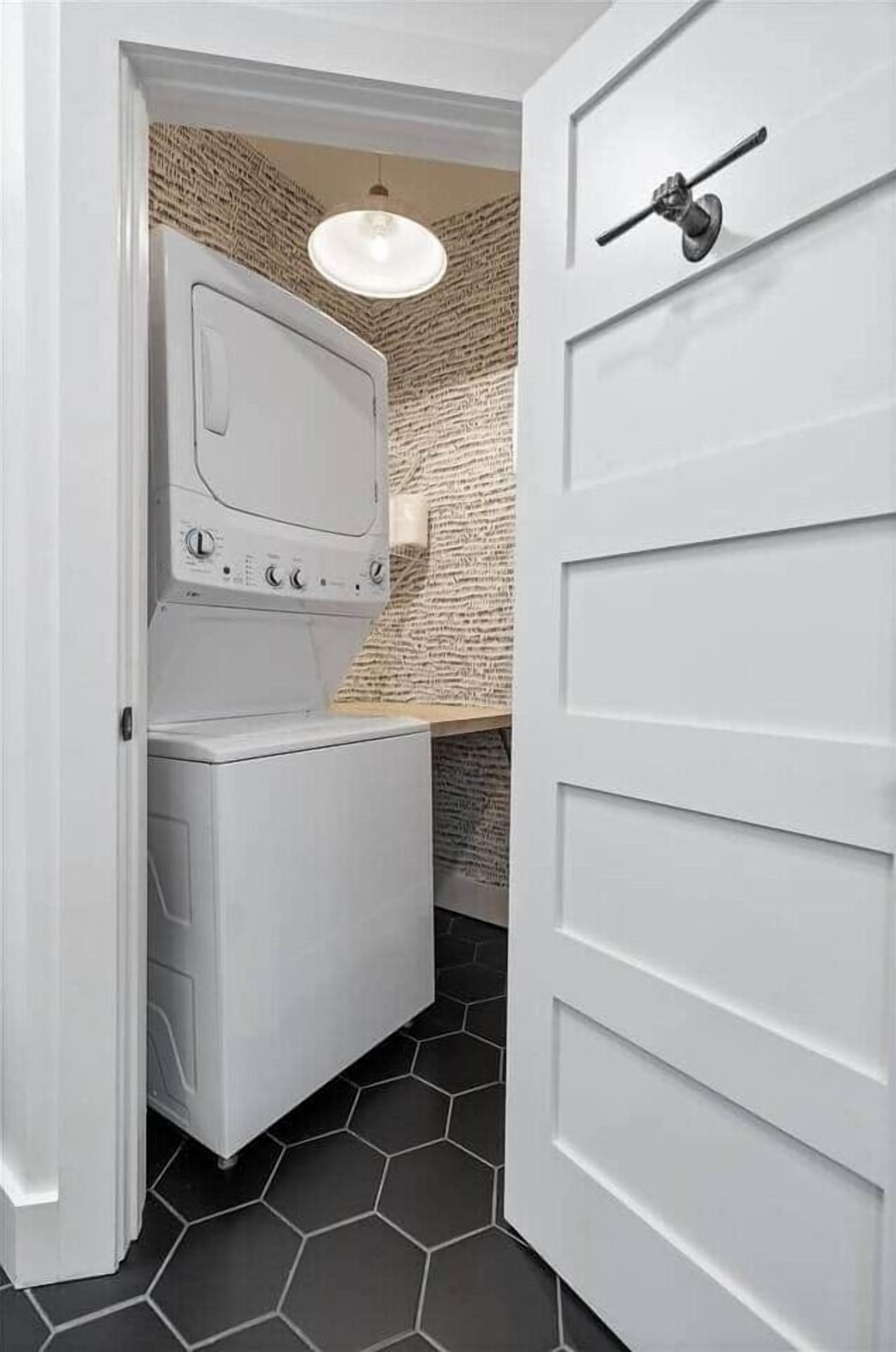 Un cuarto de lavandería con lavadora y secadora, una pared con textura y una puerta con picaporte.