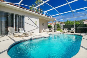 A swimming pool with lounge chairs, a covered patio, and a view of the surrounding area.