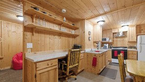 A wooden interior with a kitchen area, including a stove, microwave, and cabinets.