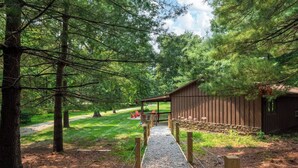A gravel pathway leading to a wooden structure with a covered seating area and a stone wall.