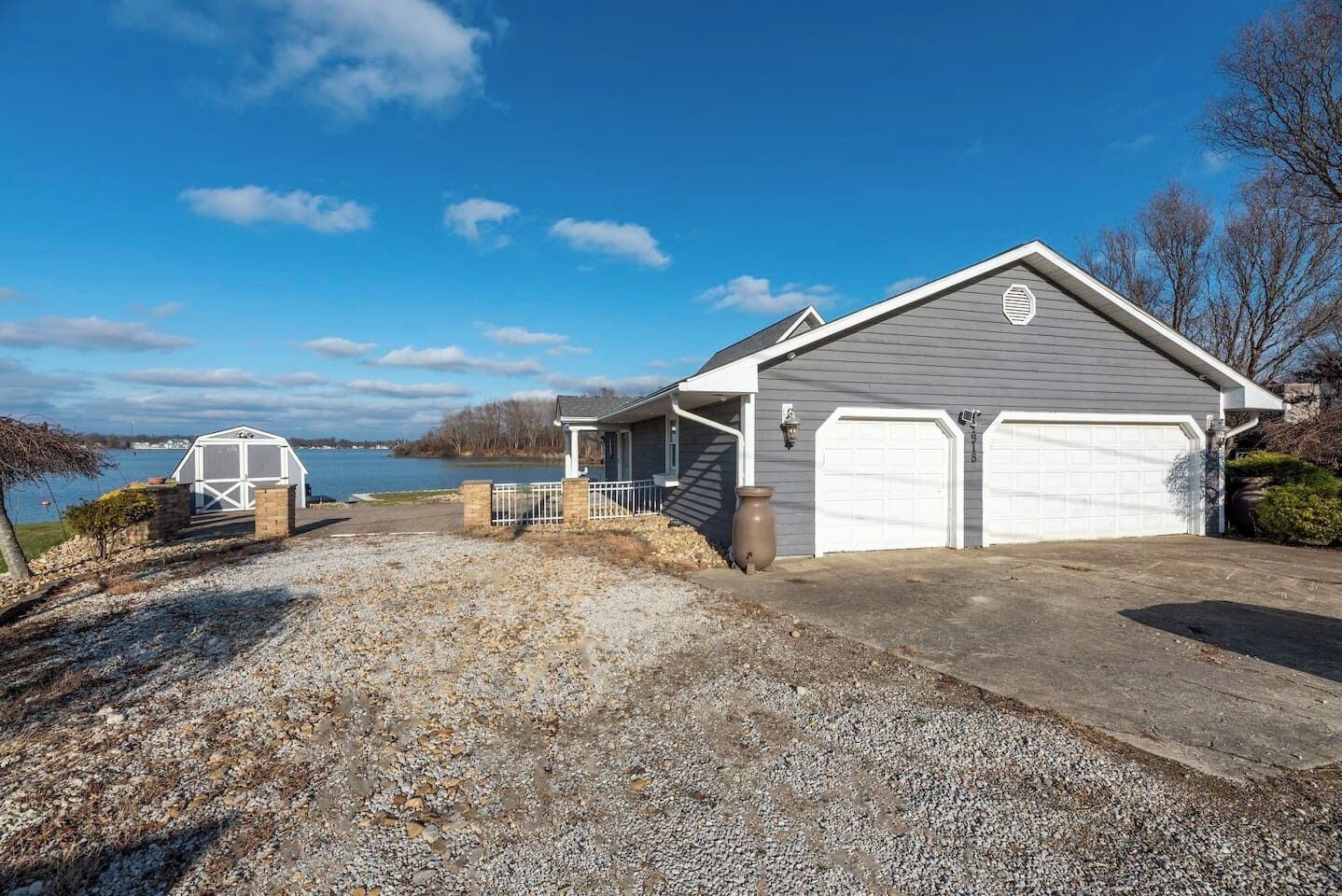 A house with a garage, a covered porch, and a view of a lake.