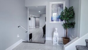 Un intérieur moderne agrémenté d’un escalier, d’une plante en pot et d’une œuvre d’art encadrée.