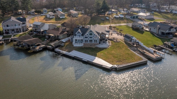 Une propriété au bord du lac, dotée d’un quai, d’une grande maison avec un porche et de plusieurs maisons plus petites.